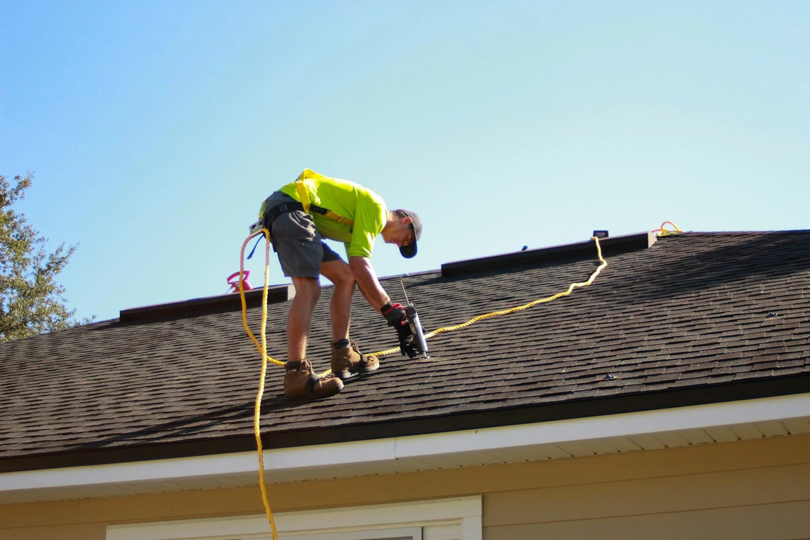 Roofer fastening shingles with a drill during a roof repair